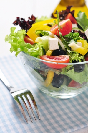 Greek salad in glass bowl on wooden background closeupの写真素材