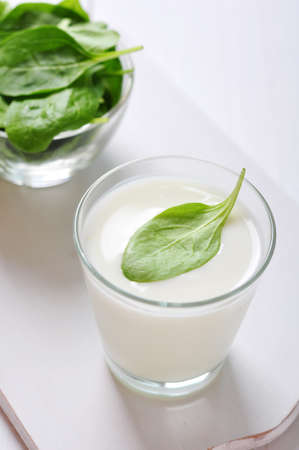 Yogurt with spinach in a glass on wooden cutting boardの写真素材