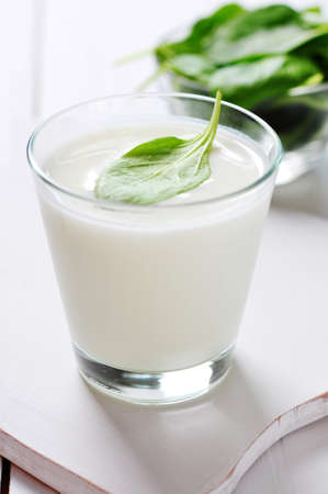Yogurt with spinach in a glass on wooden cutting boardの写真素材