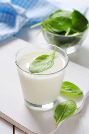 Yogurt with spinach in a glass on wooden cutting boardの写真素材
