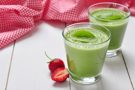 Spinach smoothies in glass served with strawberry on a wooden backgroundの写真素材