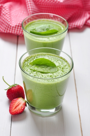 Spinach smoothies in glass served with strawberry on a wooden backgroundの写真素材