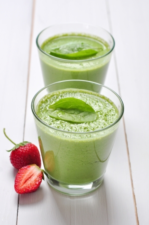 Spinach smoothies in glass served with strawberry on a wooden backgroundの写真素材