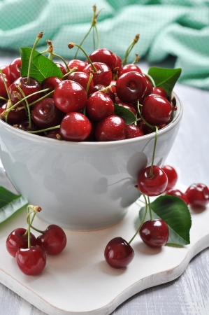 Fresh red cherries in a big mug on cutting boardの写真素材