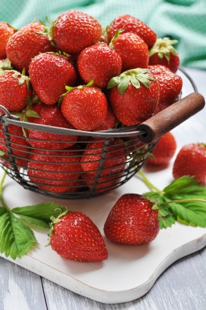 Fresh red strawberries in a big metal basket on wooden backgroundの写真素材