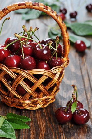 Some beautiful sweet cherry in a basket  on a wooden backgroundの写真素材