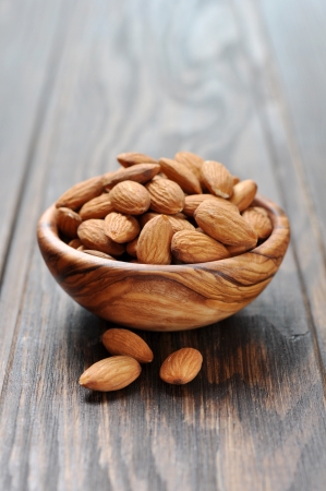 Almonds in a wooden bowl closeup on wooden backgroundの写真素材