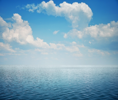 Blue sea with waves and sky with airy cloudsの写真素材