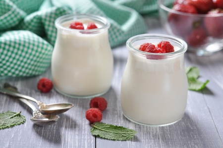 yogurt with ripe fresh raspberry in jars on wooden backgroundの写真素材