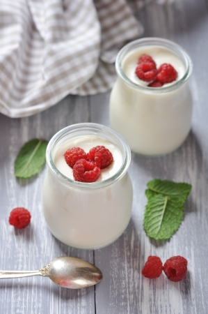 yogurt with ripe fresh raspberry in jars on wooden backgroundの写真素材