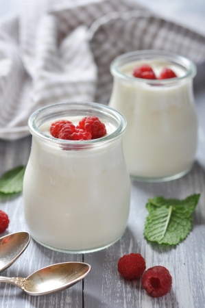yogurt with ripe fresh raspberry in jars on wooden backgroundの写真素材
