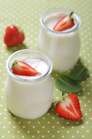 yogurt with ripe fresh strawberry in jars on green backgroundの写真素材