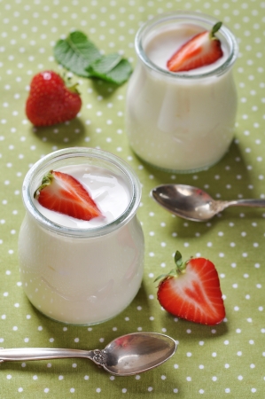 yogurt with ripe fresh strawberry in jars on green backgroundの写真素材