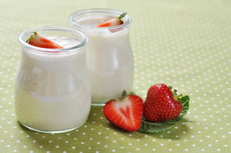 yogurt with ripe fresh strawberry in jars on green backgroundの写真素材