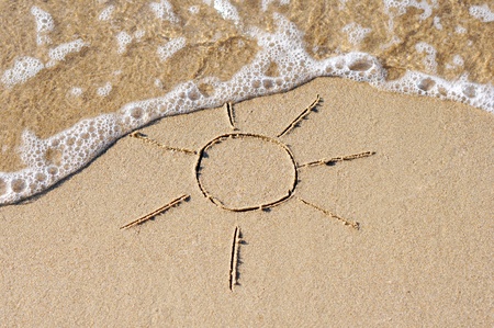 Drawing of the  sun on sand with sea waveの写真素材