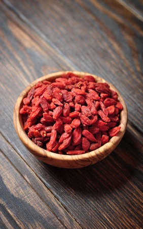 wooden bowl with goji berries on the table closeupの写真素材