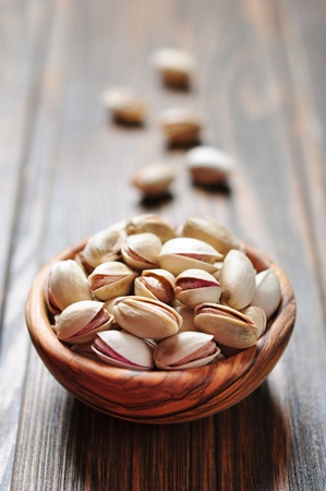 close up of a bowl of pistachio nuts over wooden backgroundの写真素材