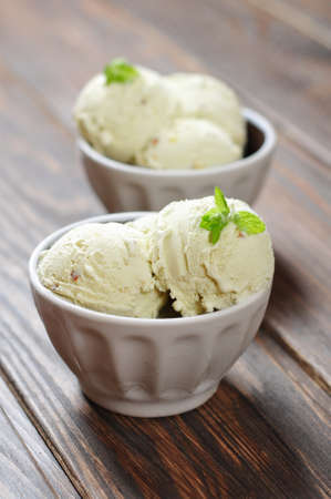 Vanilla ice cream with mint in ceramic bowl on wooden backgroundの写真素材