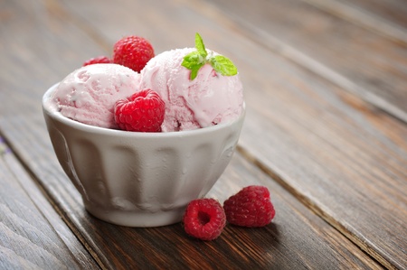 Raspberry ice cream with mint in ceramic bowl with fresh berries on wooden backgroundの写真素材
