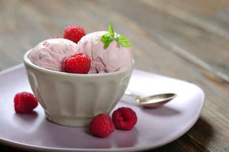 Raspberry ice cream with mint in ceramic bowl with fresh berries on wooden backgroundの写真素材