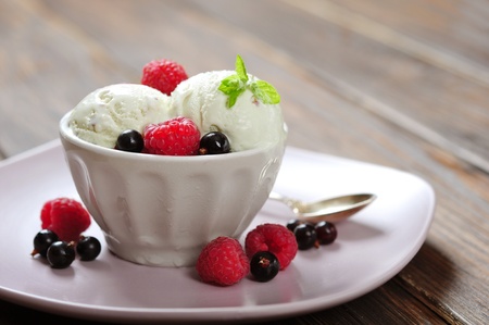 Raspberry ice cream with mint in ceramic bowl with fresh berries on wooden backgroundの写真素材