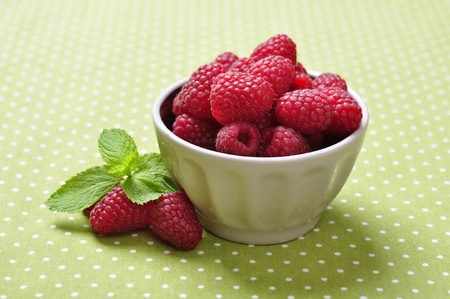 bowl of fresh raspberry on green backgroundの写真素材