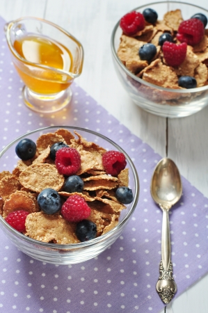 cereal flakes with raspberry and blueberry in glass bowlの写真素材