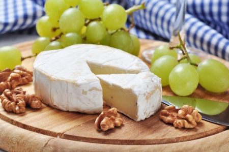 Camembert on wooden cutting board with grape and walnut closeupの写真素材