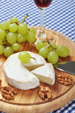 Camembert on wooden cutting board with grape and walnut closeupの写真素材
