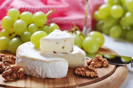 Camembert on wooden cutting board with grape and walnut closeupの写真素材