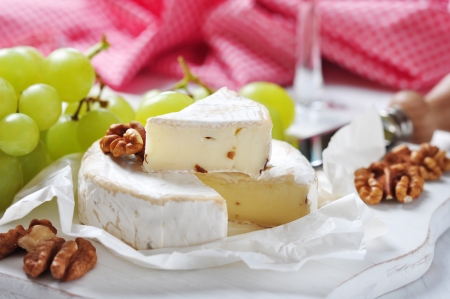 Camembert on wooden cutting board with grape and walnut closeupの写真素材