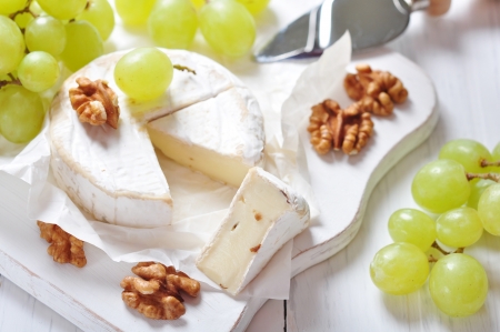 Camembert on wooden cutting board with grape and walnut closeupの写真素材
