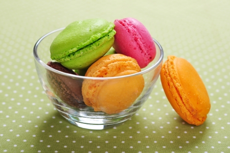 Colorful macaroons in glass bowl over green backgroundの写真素材