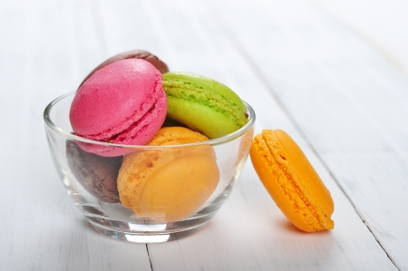 Colorful macaroons in glass bowl over wooden backgroundの写真素材