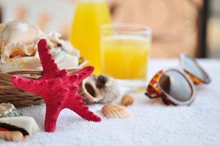 Beautiful marine still life of little basket full of seashells with sunglasses and juiceの写真素材