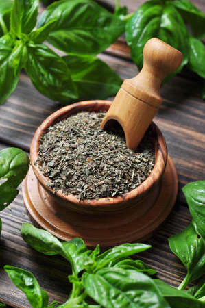 Dry basil in wooden bowl and fresh basil on wooden backgroundの写真素材