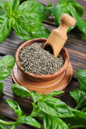 Dry basil in wooden bowl and fresh basil on wooden backgroundの写真素材