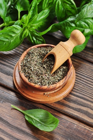Dry basil in wooden bowl and fresh basil on wooden backgroundの写真素材