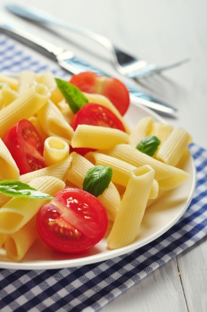 Penne pasta with cherry tomatoes and basil closeupの写真素材