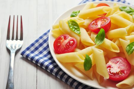 Penne pasta with cherry tomatoes and basil closeupの写真素材