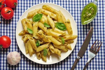Penne pasta with pesto sauce and basil on white plateの写真素材