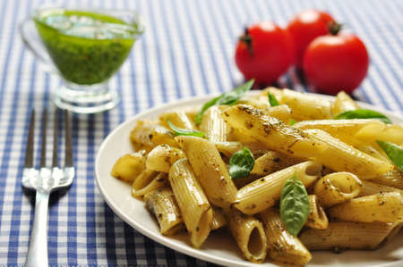 Penne pasta with pesto sauce and basil on white plateの写真素材
