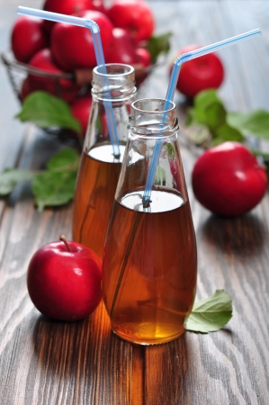 Apple cider  in glass bottle and basket with fresh applesの写真素材
