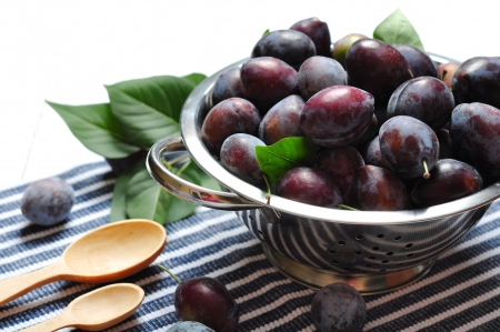 Fresh plum in metal bowl on wooden backgroundの写真素材