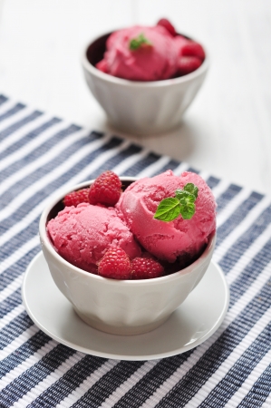 Raspberry ice cream in ceramic bowl with fresh berries and mintの写真素材