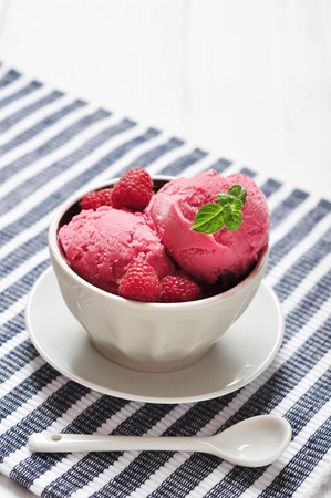 Raspberry ice cream in ceramic bowl with fresh berries and mintの写真素材