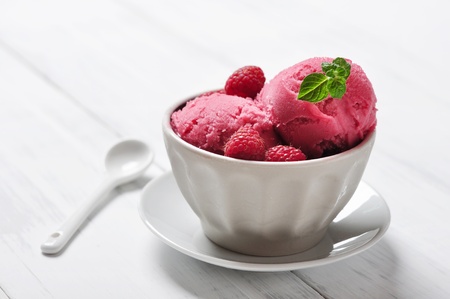 Raspberry ice cream in ceramic bowl with fresh berries and mintの写真素材