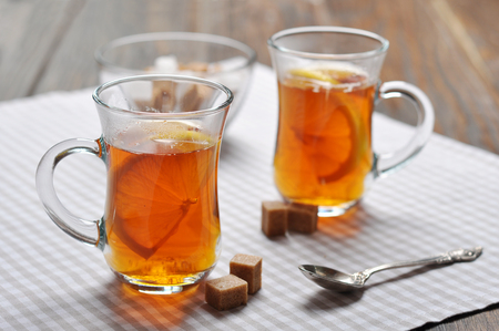 Tea with lemon in glass cups on checkered napkinの写真素材