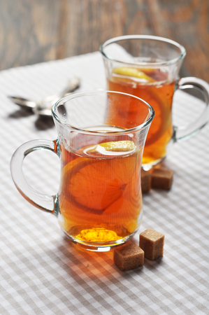 Tea with lemon in glass cups on checkered napkinの写真素材