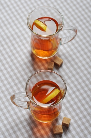 Tea with lemon in glass cups on checkered napkinの写真素材